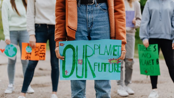 Bild på ett barn som håller i en skylt där det står "our planet our future" 